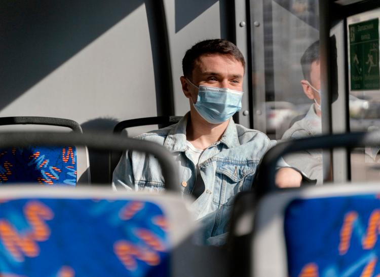 young-man-travelling-by-city-bus-wearing-surgical-mask.jpg