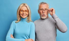 cheerful-middle-aged-woman-and-her-husband-pensioner-reacts-on-shocking-news-keeps-hand-on-spectacles-isolated-over-blue-wall.jpg