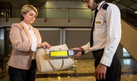 airport-security-officer-using-a-metal-detector-to-check-a-bag.jpg