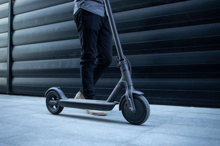 person-walking-by-his-electric-scooter.jpg