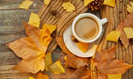 closeup-shot-of-a-cup-of-coffee-and-autumn-leaves-on-wooden-surface.jpg