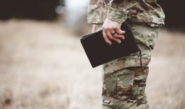 shallow-focus-shot-of-a-young-soldier-holding-a-bible-in-a-field.jpg