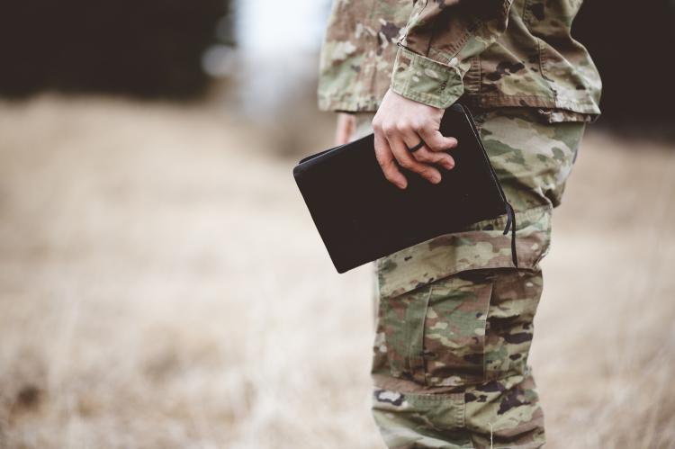 shallow-focus-shot-of-a-young-soldier-holding-a-bible-in-a-field.jpg