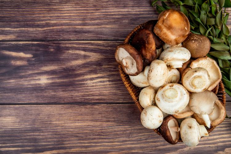 top-view-of-fresh-mushrooms-in-a-wicker-basket-on-rustic-wood-with-copy-space.jpg