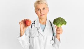 attractive-confident-mature-caucasian-female-doctor-holding-red-apple-and-green-broccoli-as-part-of-healthy-diet-to-reduce-risk-of-some-chronic-diseases-food-nutrition-and-health-concept.jpg