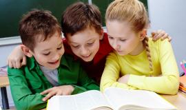 primary-students-reading-a-yellow-book-with-blackboard-background.jpg