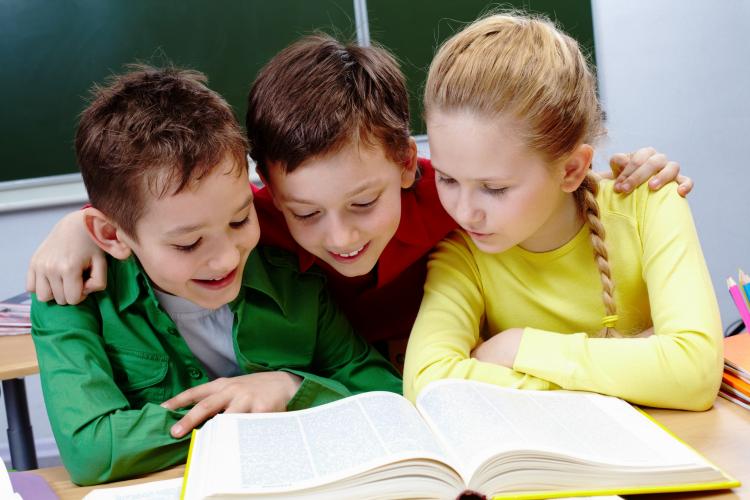 primary-students-reading-a-yellow-book-with-blackboard-background.jpg