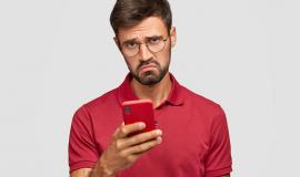 photo-of-displeased-young-unshaven-guy-holds-modern-red-smart-phone-being-unhappy-to-read-neagtive-news-in-internet-messages-with-friends-in-social-networks-connected-to-wireless-internet.jpg