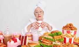 surprised-elderly-lady-with-red-lipstick-has-imbalancd-nutrition-eats-different-tasty-junk-food-drinks-cocktail-containing-much-sugar-dressed-in-domestic-clothes.jpg