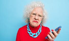 photo-displeased-wrinkled-old-curly-woman-holds-mobile-phone-checks-message-frowns-face-wears-spectacles-red-jumper-necklace_273609-50104.jpg