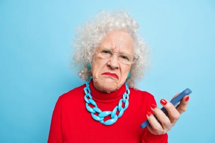 photo-displeased-wrinkled-old-curly-woman-holds-mobile-phone-checks-message-frowns-face-wears-spectacles-red-jumper-necklace_273609-50104.jpg