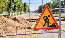 road-sign-roadworks-ahead-on-the-fence-against-the-background-of-a-trench-across-an-empty-street_533998-3392.jpg