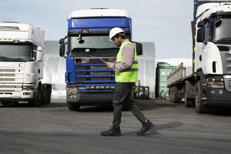 full-shot-man-walking-by-trucks-fleet.jpg