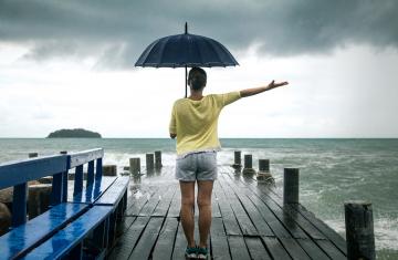 young-girl-on-pier-with-umbrella-stands-with-his-back-to-the-sea.jpg