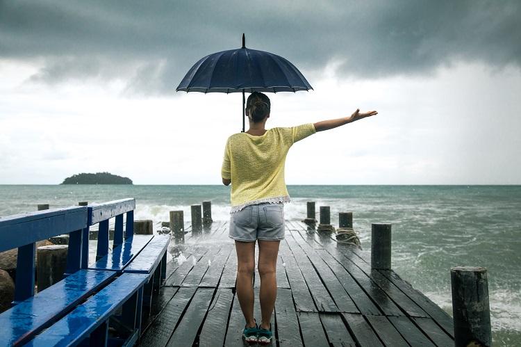 young-girl-on-pier-with-umbrella-stands-with-his-back-to-the-sea.jpg