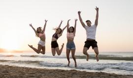 full-shot-friends-jumping-on-beach.jpg