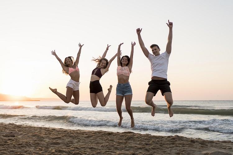 full-shot-friends-jumping-on-beach.jpg