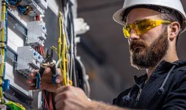 a-male-electrician-works-in-a-switchboard-with-an-electrical-connecting-cable.jpg