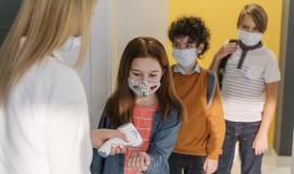 female-teacher-with-medical-mask-checking-student-s-temperature-in-school.jpg