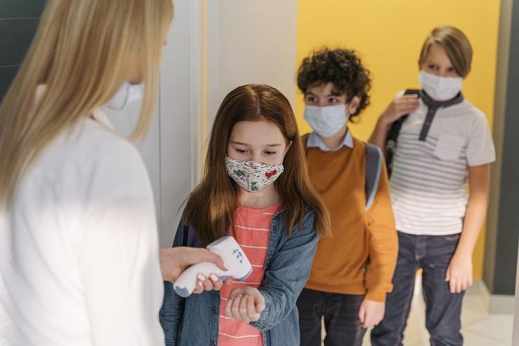 female-teacher-with-medical-mask-checking-student-s-temperature-in-school.jpg