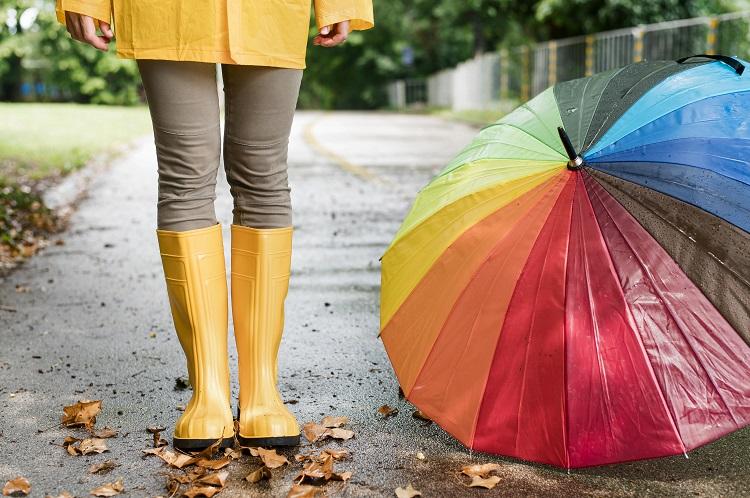 woman-in-rain-boots-standing-next-to-colorful-umbrella.jpg