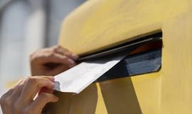 close-up-woman-at-mailbox-with-envelope.jpg