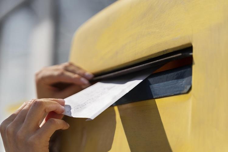 close-up-woman-at-mailbox-with-envelope.jpg