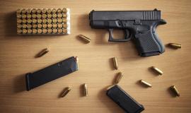 gun-with-box-of-ammunition-and-bullets-on-wooden-wall.jpg