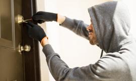 profile-view-of-a-man-with-a-hoodie-trying-to-pick-a-lock-in-a-house-and-forcing-his-entry.jpg