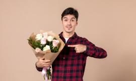 front-view-young-male-holding-beautiful-flowers-brown-wall_140725-152632.jpg