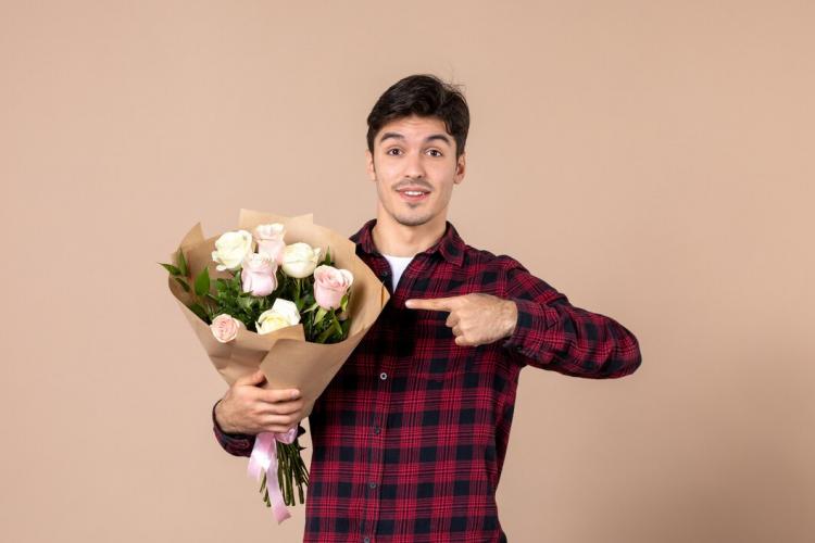 front-view-young-male-holding-beautiful-flowers-brown-wall_140725-152632.jpg