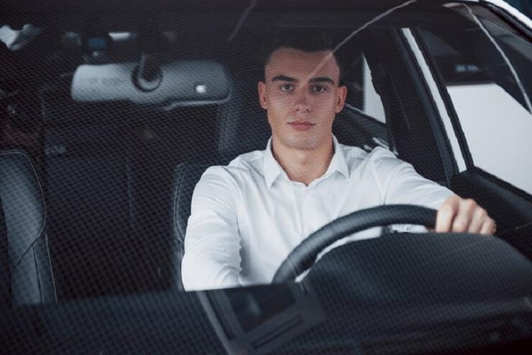 young-man-sits-newly-bought-car-holding-his-hands-rudder_146671-14762.jpg