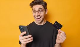 photo-cheerful-surprised-adult-man-stares-smartphone-with-unbelievable-gaze-shocked-receive-big-amount-money-wears-spectaces-casual-black-t-shirt-isolated-yellow-background_273609-62856.jpg