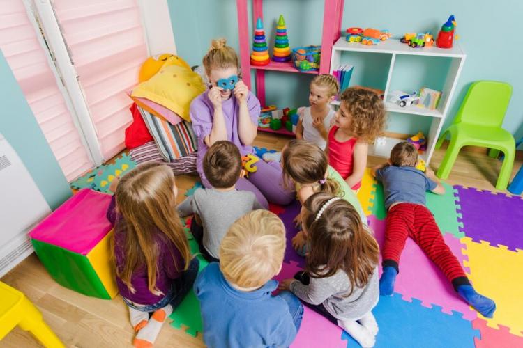 young-engaged-teacher-sitting-with-group-preschool-children-floor-during-lesson-process-learning-can-be-fun-room-with-colorful-mats-floor-multicolor-furniture_290431-24389.jpg