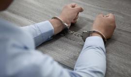 selective-focus-shot-male-hands-handcuffs-wooden-table_181624-57683.jpg