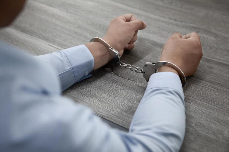 selective-focus-shot-male-hands-handcuffs-wooden-table_181624-57683.jpg