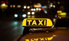 yellow-and-black-sign-of-taxi-placed-on-top-of-a-car-at-night.jpg