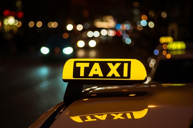 yellow-and-black-sign-of-taxi-placed-on-top-of-a-car-at-night.jpg