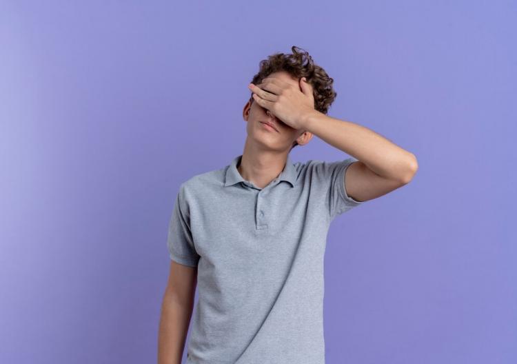 young-man-black-glasses-wearing-grey-polo-shirt-covering-eyes-with-hand-tired-bored-standing-blue-wall_141793-57512.jpg