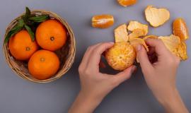 top-view-woman-peels-orange-from-peel-with-basket-gray-background_141793-52170.jpg