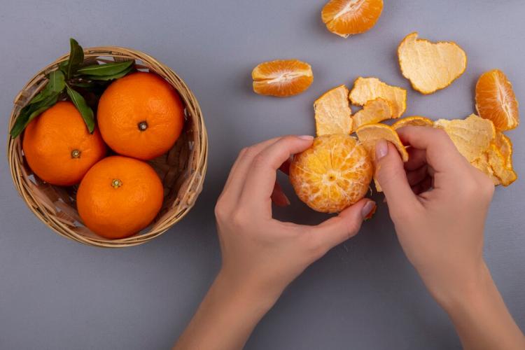 top-view-woman-peels-orange-from-peel-with-basket-gray-background_141793-52170.jpg