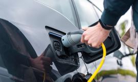 man-plugging-in-charger-into-an-electric-car-at-charge-station.jpg