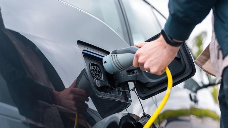 man-plugging-in-charger-into-an-electric-car-at-charge-station.jpg