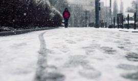 low-angle-shot-of-a-person-walking-on-the-snow-covered-sidewalk-under-the-snow.jpg